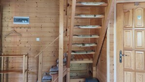 A wooden interior with a staircase, a door, and a trash bin. - Wooden House in Kolczewo Near Baltic Sea Beach (gmina Wolin)