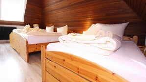 A wooden-paneled room with two beds, each with neatly folded towels and pillows. - Ferienwohnung in Westerland (Sylt)