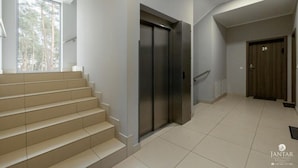 Egy modern belső tér, lépcsővel, tolóajtóval és kilátással a kinti fákra.