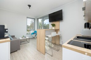A modern, well-lit room with a kitchen area, a dining table, and a sofa. - Apartment Very Close to the Seaside Beach (Rewal)