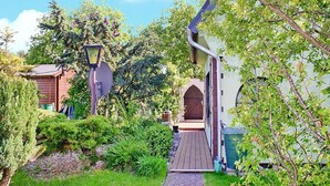 Un chemin de jardin menant à un bâtiment doté d’une porte en bois et d’une antenne parabolique.