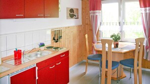 Une cuisine avec des meubles de couleur rouge, un évier et une fenêtre avec des rideaux.
