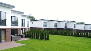 Un immeuble résidentiel moderne doté d’une pelouse bien entretenue et de haies soigneusement taillées.