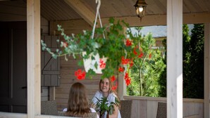 A wooden porch with a hanging lantern, a bench, and a potted plant. - Bungalow in Miedzyzdroje With a Terrace (Miedzyzdroje)