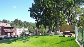 A grassy outdoor area with a playground, a picnic table, and a small wooden structure. - Bungalow in Miedzyzdroje With a Terrace (Miedzyzdroje)
