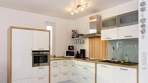 Eine moderne Küche mit weißen Schränken, Edelstahlgeräten und einer Holz Arbeitsplatte.