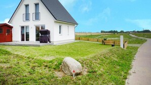 Ein weißes Haus mit grauem Dach, einer roten Garage und einem großen Felsen im Vordergrund.