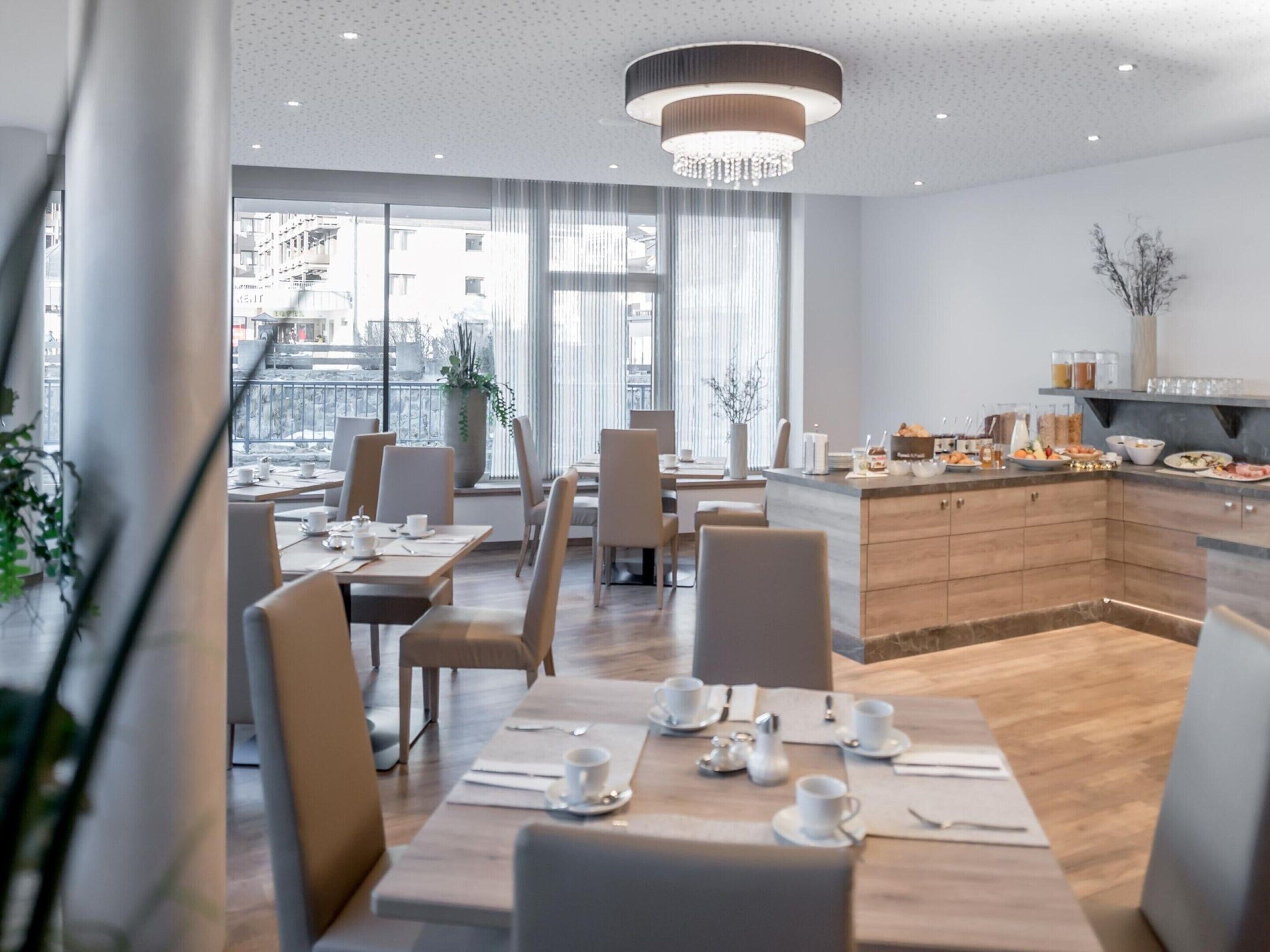 Un espace de salle à manger moderne avec une longue table, des chaises et un comptoir de cuisine visible au fond.