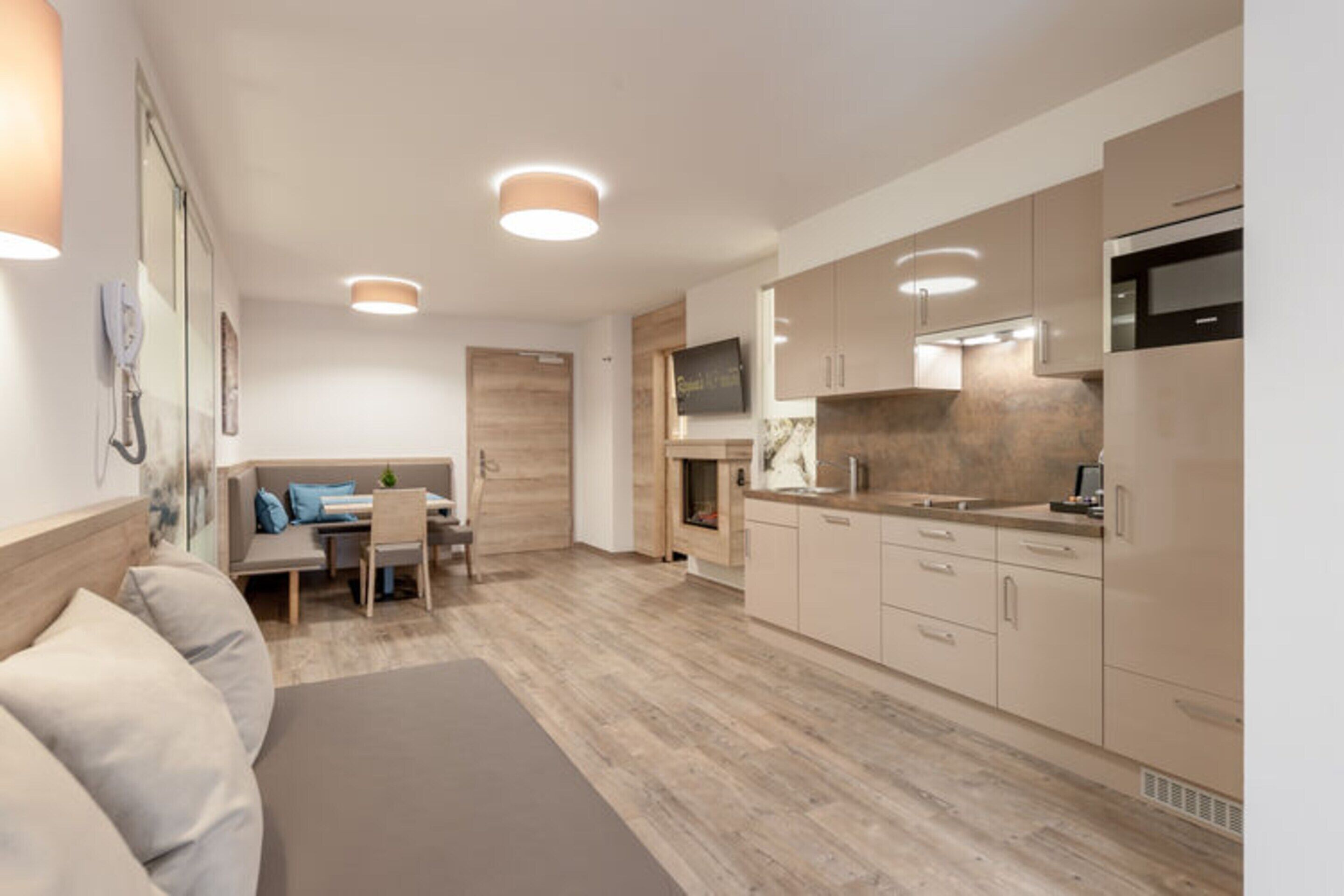Een moderne keuken met houten kasten, een eethoek met tafel en stoelen, en een bank.