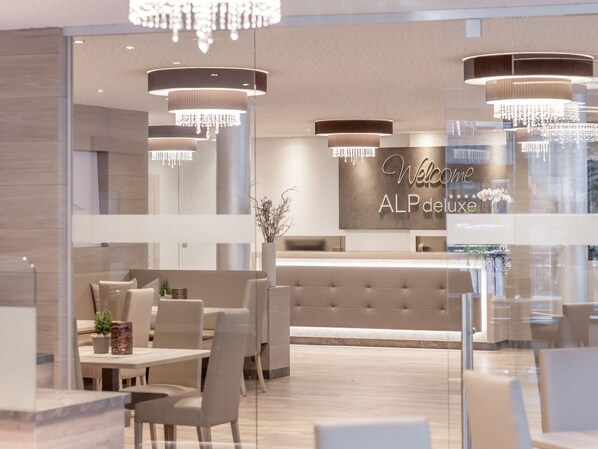 Un moderno vestíbulo de hotel con mostrador de recepción, zona de estar y candelabros.