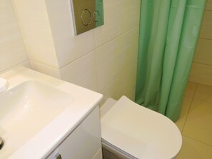 A bathroom with a white sink, a toilet, and a green shower curtain. - Apartment in Rewal Near the Beach (Rewal)