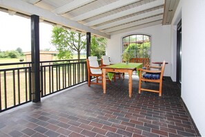 A covered patio with a brick floor, a table with chairs, and a view of the outdoors. - House Spreewiese, Neuendorf am See (Unterspreewald)