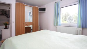 Una camera da letto con un letto, un armadio, una televisione e una finestra con tende.