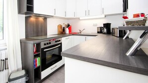 Una cucina moderna con mobili bianchi, forno integrato e lavello in acciaio inossidabile.