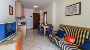 Sala de estar con televisor, sofá y comedor.