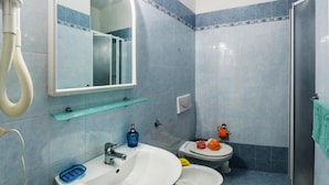 Un baño con lavamanos, dos inodoros, un espejo y ducha.