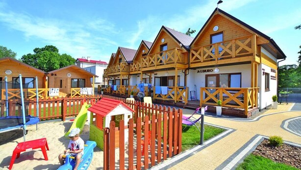 A row of wooden cabins with a playground area in front. - Comfortable Holiday Homes, Mielno (Mielno)
