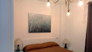 Une chambre à coucher avec une couvre-lit marron, un tableau au mur et deux lampes de chevet.