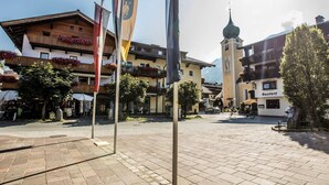 A square with cobblestone pavement, surrounded by traditional European buildings with balconies and flower boxes. - Chalet Rabl, Westendorf (Westendorf)