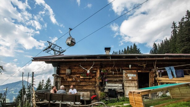 A rustic wooden cabin with a wooden deck and a ski lift cable above. - Chalet Rabl, Westendorf (Westendorf)