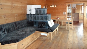 A wooden cabin interior with a sofa, a dining table, and a kitchen area. - Chalet Rabl, Westendorf (Westendorf)