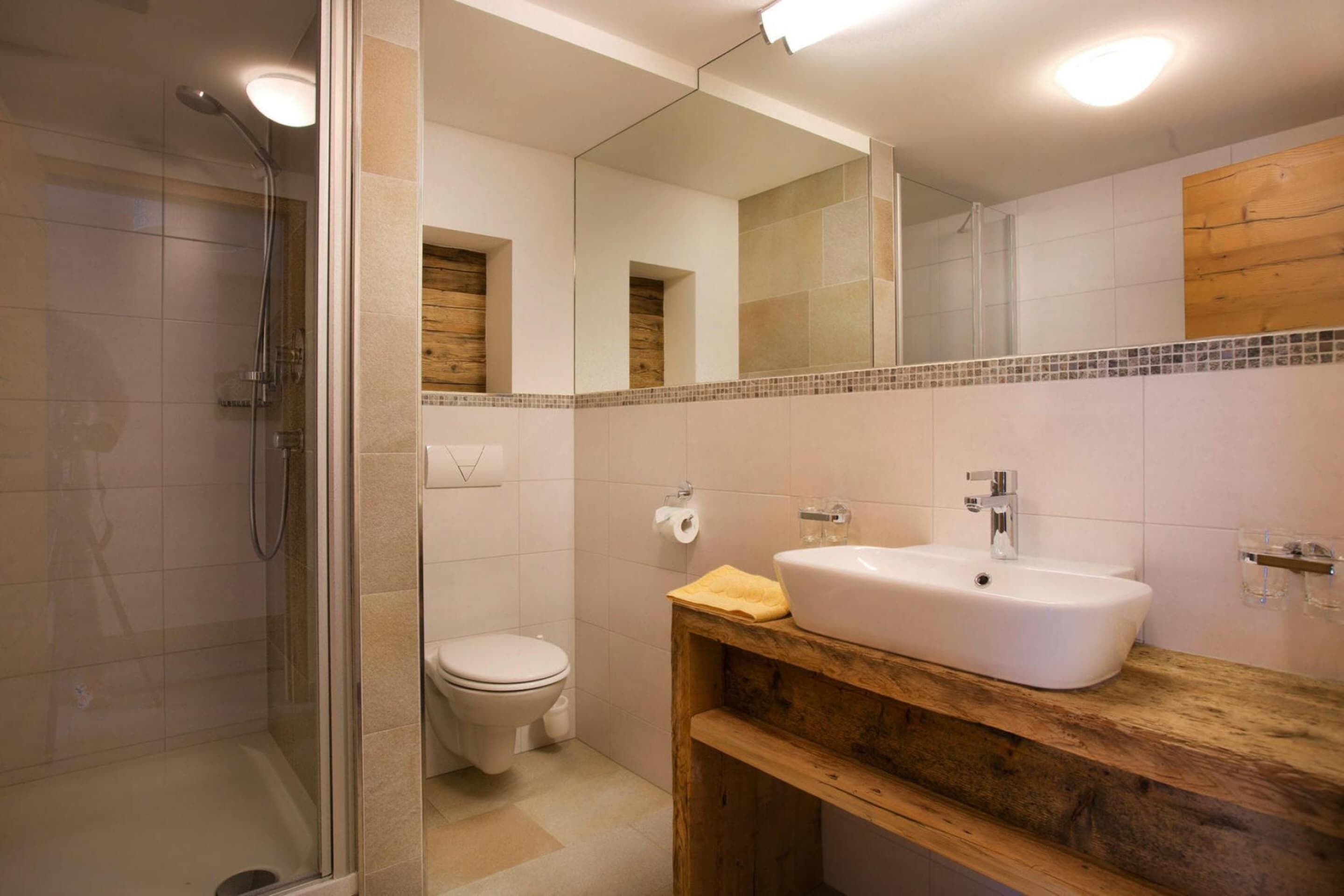 Ein modernes Badezimmer mit einer Duschkabine, einer Toilette und einem Waschbecken mit Holzschrank.