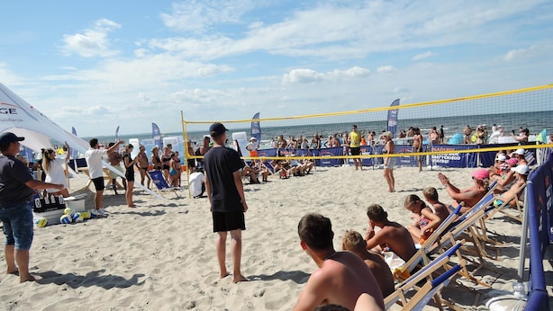 Un match de volleyball de plage avec des spectateurs et des joueurs.