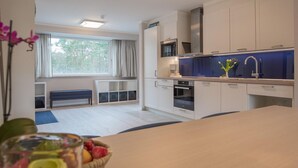 Una cocina moderna con armarios blancos, una encimera azul y un horno empotrado.