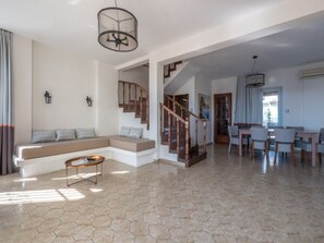 A spacious living area with a staircase, a dining area, and a seating area with a sofa and coffee table.