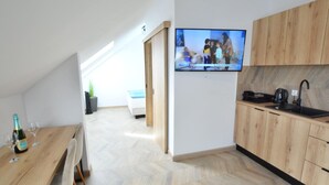 Una cocina moderna con armarios de madera, horno empotrado y un televisor de pantalla plana grande montado en la pared.