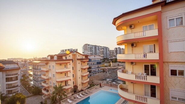 A multi-story residential building with a swimming pool, balconies, and a clear view of the surrounding area. - Sevgi Tatil Sitesi (Alanya)