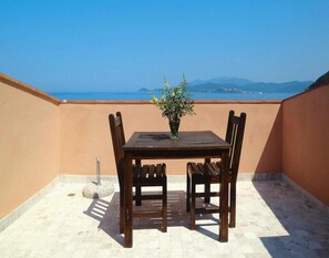 Enjoy a peaceful outdoor space with a table and chairs, surrounded by walls and offering a view of the sea and distant mountains.