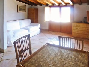Relax in this spacious room with a high ceiling, featuring a sofa, cabinet, and woven table.