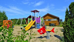 Un espace de jeux pour enfants avec un toboggan, des balançoires et un ensemble de balançoires en forme de requin.