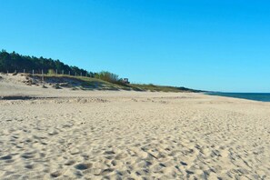 Een breed zandstrand met zachte hellingen en een helderblauwe lucht.