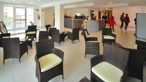 Un hall d’entrée avec des meubles en osier, un comptoir de réception et un extincteur.