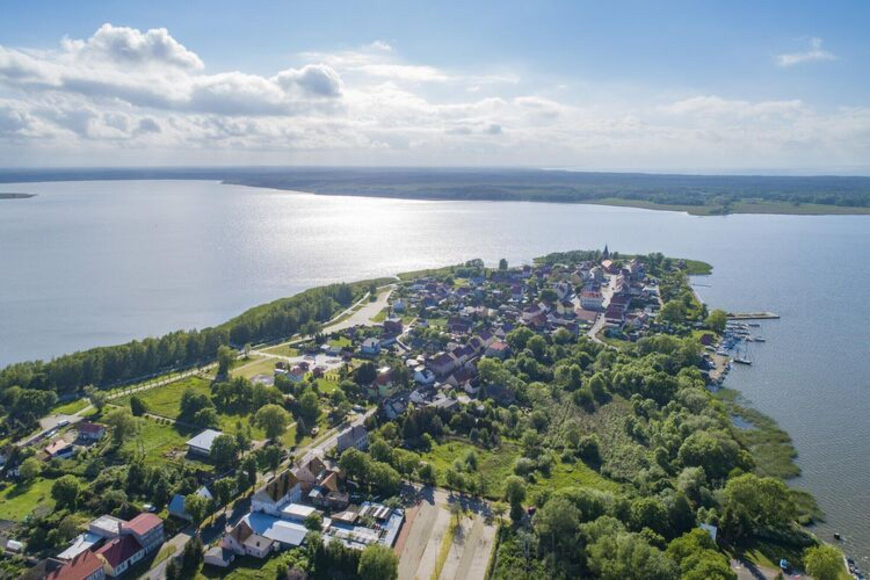 An aerial view of a lakeside village with houses, docks, and a clear sky.