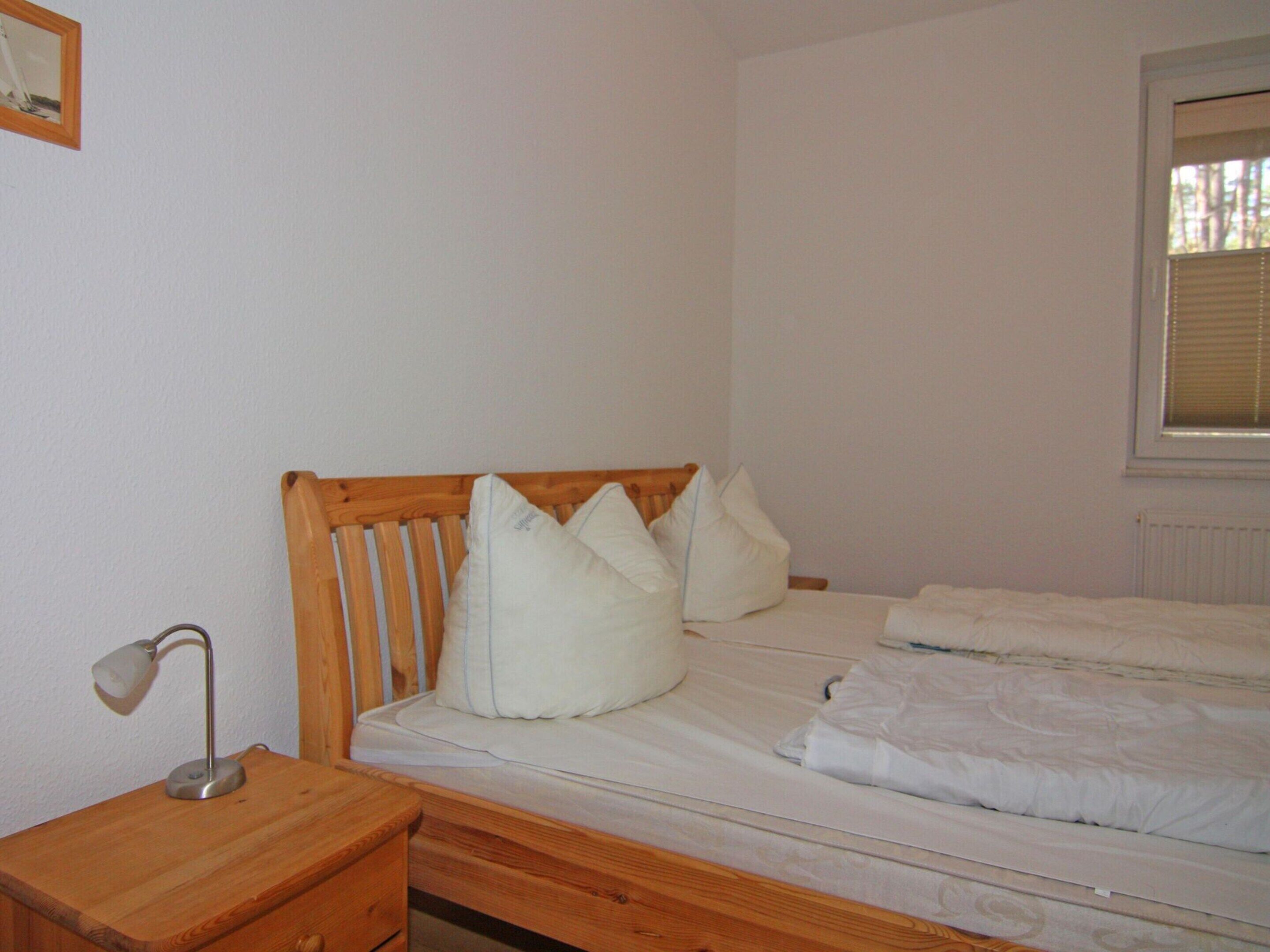 Une chambre à coucher avec une tête de lit en bois, une table de chevet avec une lampe et une fenêtre avec des stores.