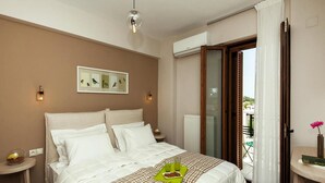 A bedroom with a bed, a bedside table, a wall-mounted light, a window with curtains, and a balcony view. - Holiday Villa With hot tub in Adele (Rethymno)