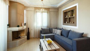 A modern living room with a grey sofa, a wooden coffee table with yellow candles, and a brick fireplace. - Holiday Villa With hot tub in Adele (Rethymno)