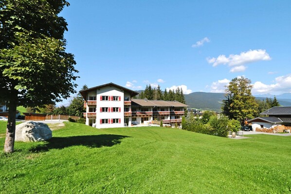 A multi-story building with a flat roof, surrounded by a well-maintained lawn and trees. - Apartment House Isegrim, Altenmarkt (Altenmarkt im Pongau)