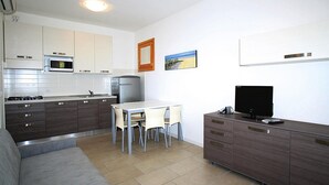 Eine moderne Küche mit Essbereich, einer Couch und einem Fernseher auf einem Schrank.