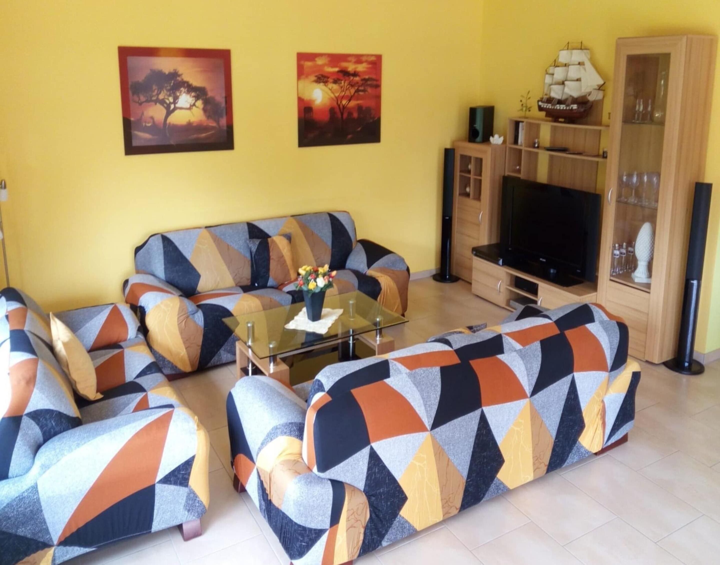 Una sala de estar con un sofá, una mesa de centro, un televisor y un mueble con objetos decorativos.