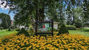 A sign for 'Gondola House' surrounded by a field of yellow flowers. - Gondola House | Hot tub, Arcade, Walkable Getaway, Fun Central! Game Room, Hot Tub, Steps to Village... (Ellicottville)