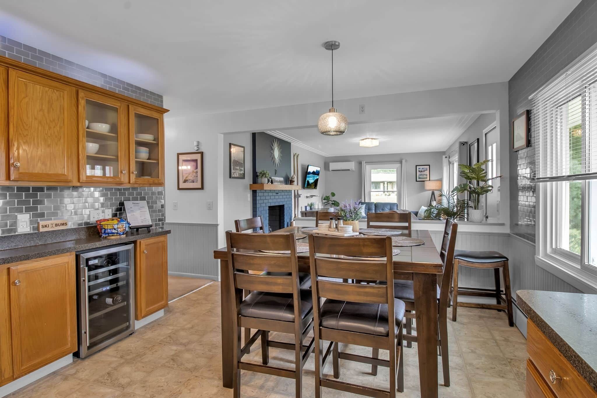 A modern kitchen with wooden cabinets, a built-in oven, and a dining area with a table and chairs.