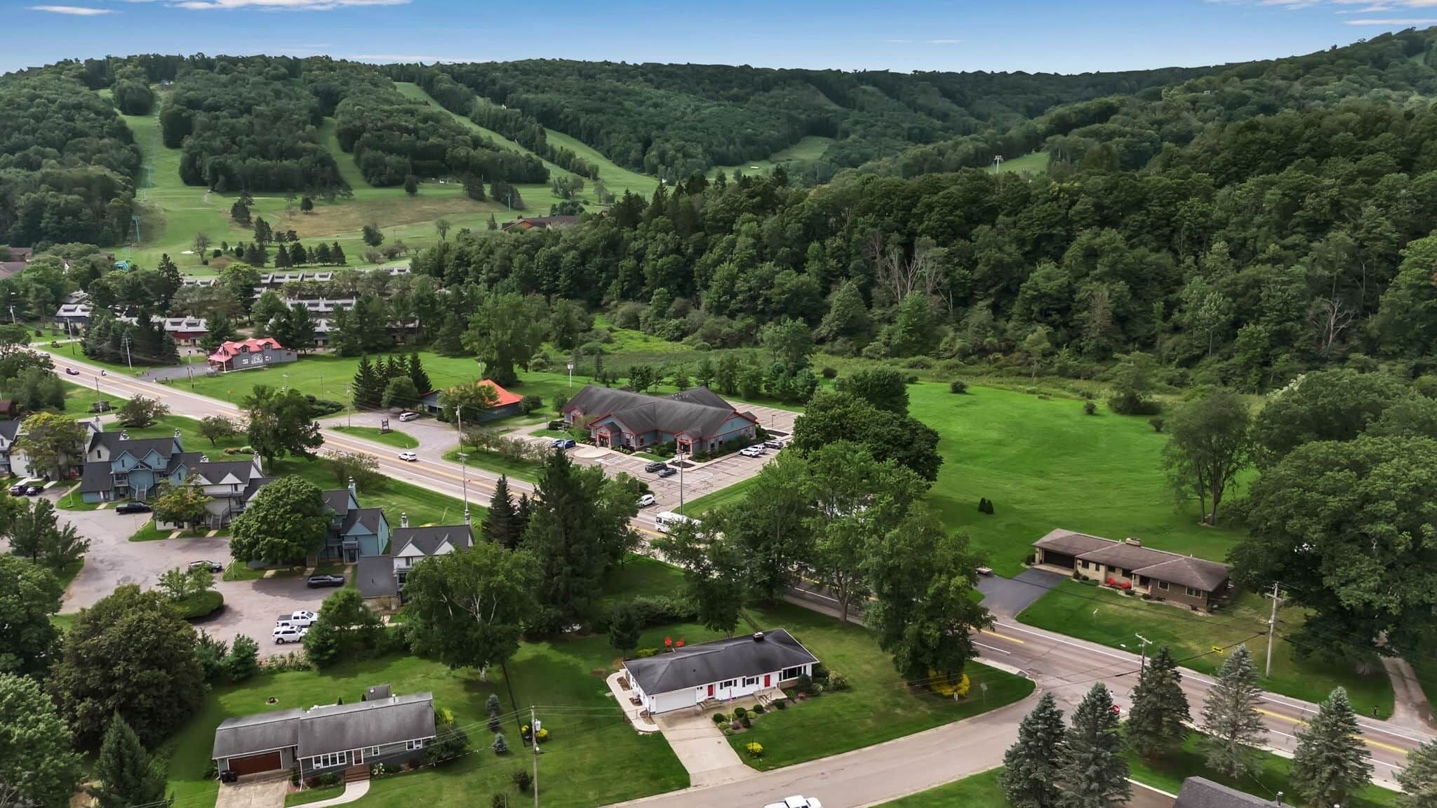 A residential area with houses, a road, and a green field.