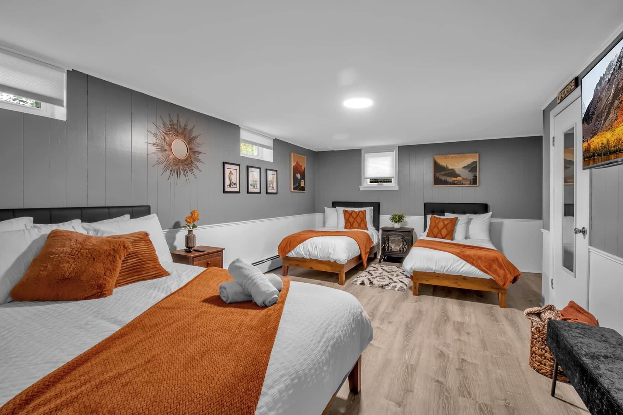 Ein modernes Hotelzimmer mit zwei Betten, einer sonnenförmigen Wanddekoration, gerahmten Bildern und einem großen Fenster.