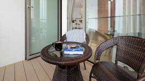 A glass-top table with a book and a cup, wicker chairs, and a sliding glass door leading to a balcony. - Apartment Close to the Sea, With Pool and Sauna (Rewal)