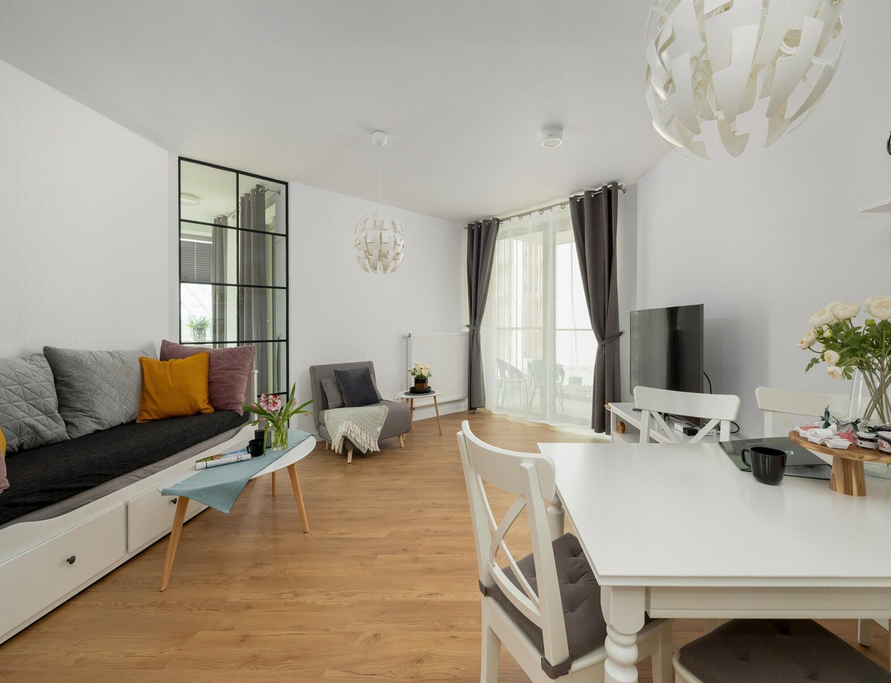 A modern living room with a sofa, a dining table, and a TV.