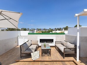 An outdoor patio with a fireplace, two sofas, a coffee table, and a large umbrella. - Central Apartment With Spectacular Terrace-formerly TUI Ferienhaus (San Bartolomé de Tirajana)